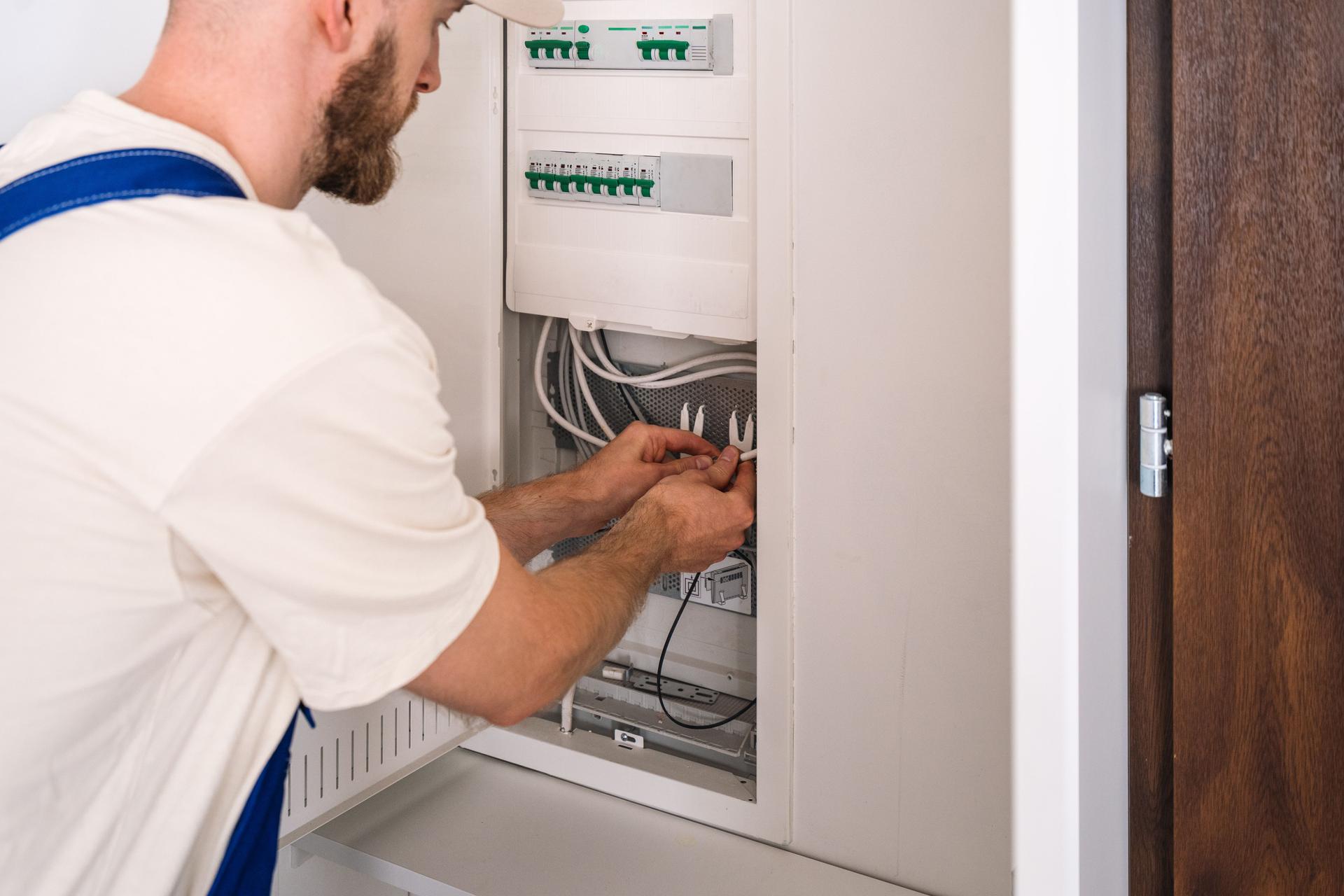 Electrician performing maintenance on electrical panel in residential building