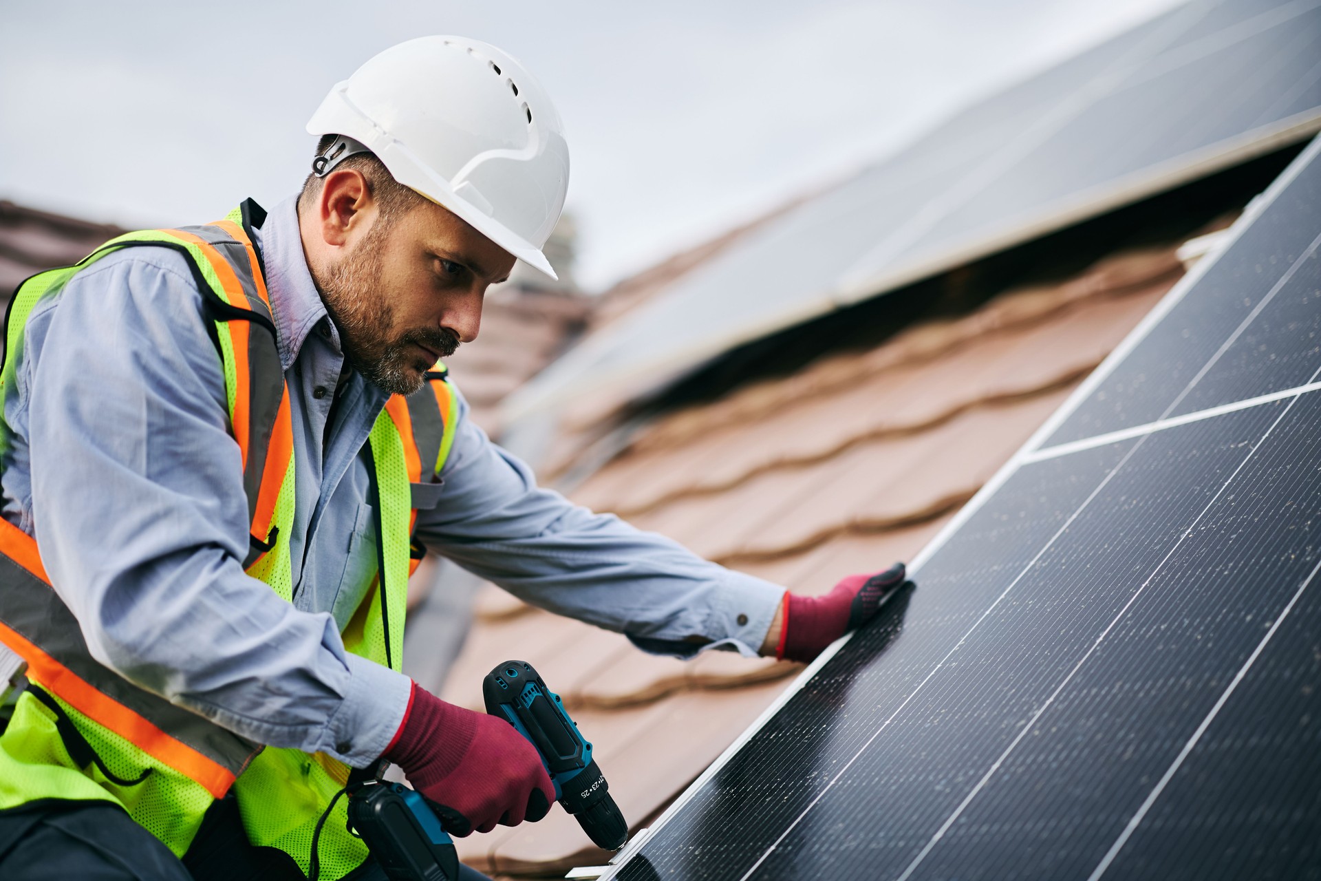 Male engineer securing solar panels to the mounting system on the roof.