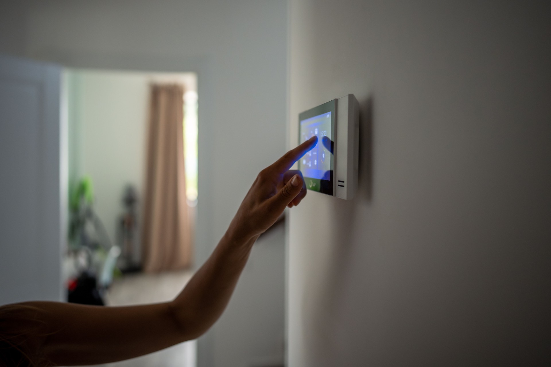 Closeup hand using smart home panel, touching screen with connected appliances device on wall.