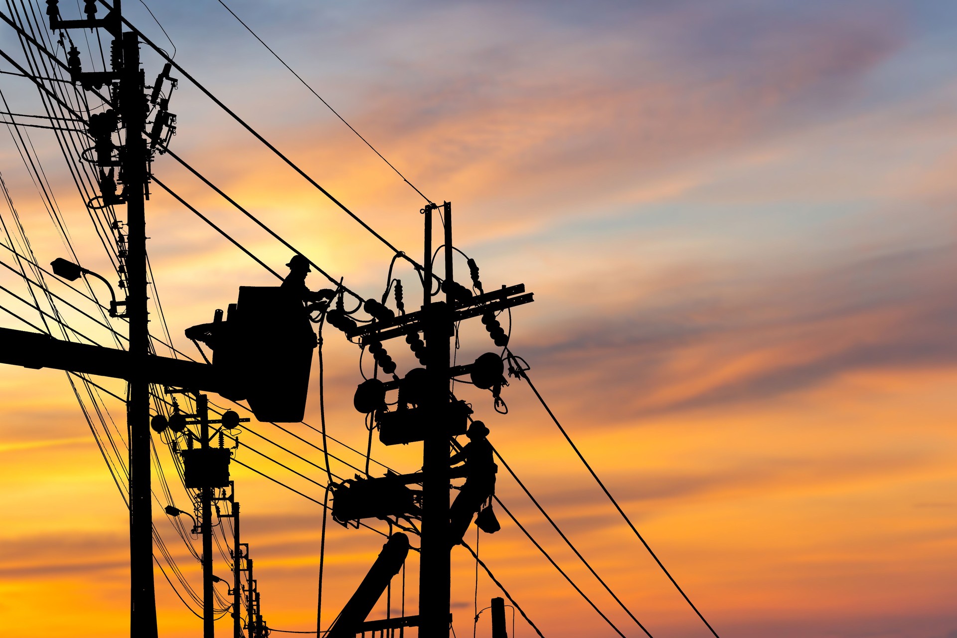 Silhouette of Electrician officer climbs a pole and uses a cable car to maintain a high voltage line system, Shadow of Electrician lineman repairman worker at climbing work on electric post power pole